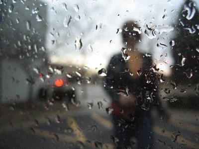 raindrops on a car window and the blurry image of a woman on the other side