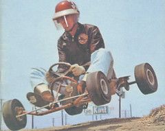 a man driving a go-kart and wearing a red helmet