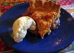 a piece of pie and a scoop of vanilla ice cream on a blue plate
