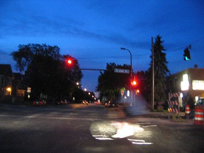 an intersection at dusk and the blur of a bicycle and its rider
