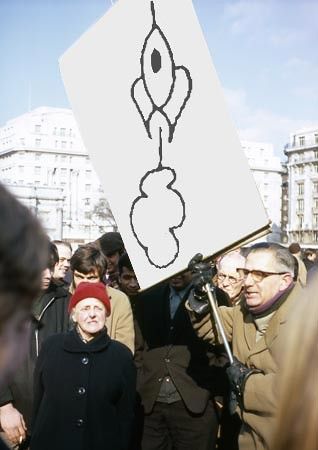 two older people protest in the cold, but the man's poster has my rocket drawing on it