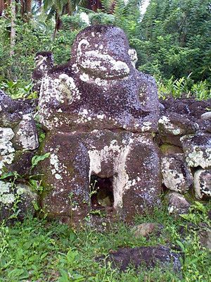 a very old and mossy piece of carved stone in a jungle