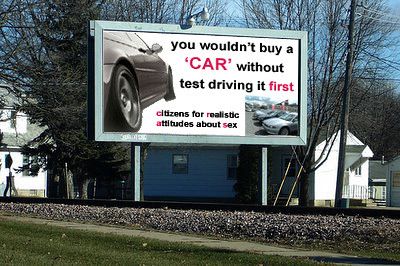 a billboard which reads "you wouldn't buy a 'car' wihtout test driving it first -- citizens for realistic attitudes about sex