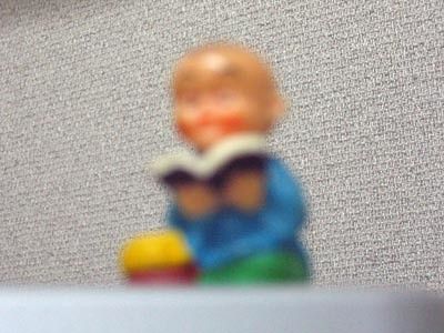 a very blurry image of a small, plastic figurine of a reading buddha
