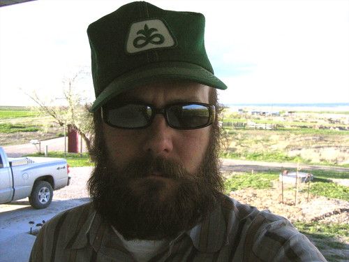 the bearded author wearing sunglasses and a Pioneer seed cap; in the background: high plains and a pickup truck