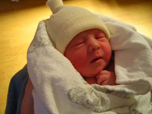 a very small baby wrapped in a blanket and wearing a stocking cap