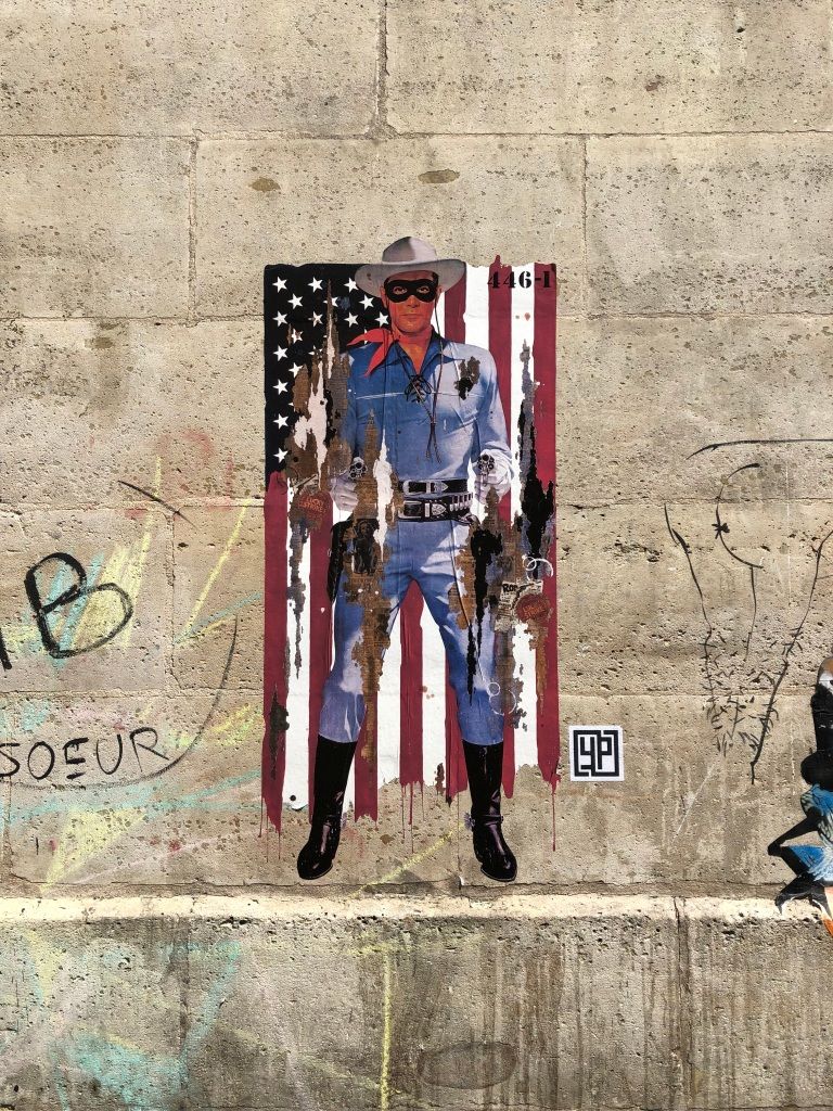 graffiti poster of the Lone Ranger in front of the American flag; the poster has been partially ripped down