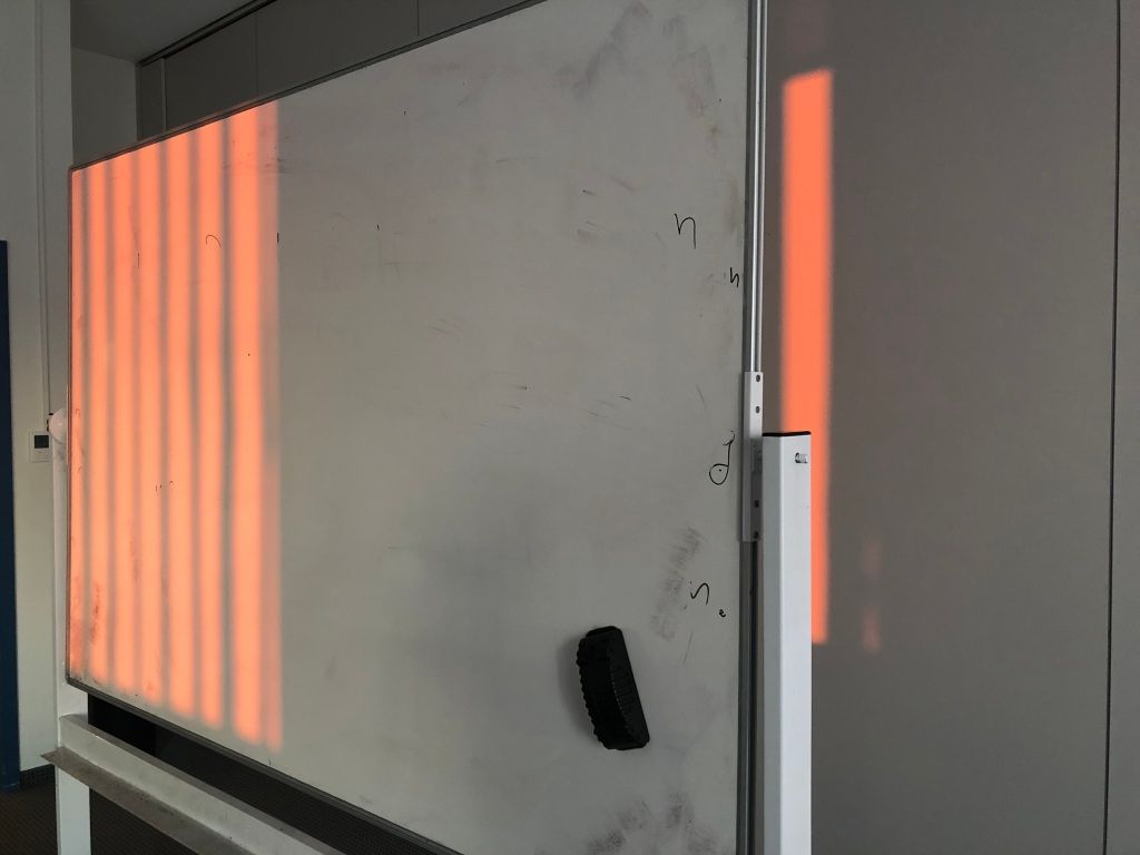 orange light through venetian blinds onto a dirty whiteboard