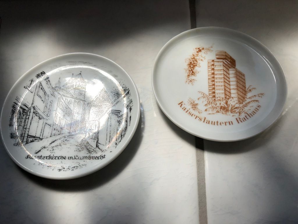 two commemorative saucers. on the left, a black and white image of the "Klosterkirche in Lambrecht." on the right, a brown and white image of the "Kaiserslautern Rathaus."